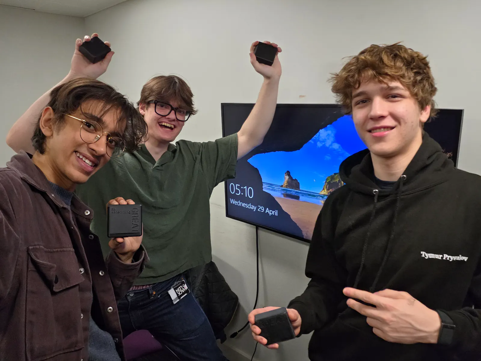 Three members of the ClearZone founding team in a meeting room, smiling and holding up early FocusField prototypes.